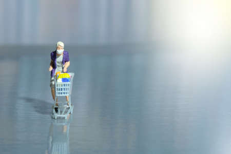 A woman doing safe solo shopping at supermarket wearing a face mask. Miniature people figurines toys conceptual photography.の写真素材