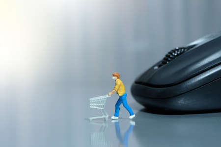 Online shopping. Women with cart in front of black mouse. Miniature people figurines toys conceptual photography.の写真素材