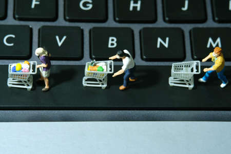Online shop concept. Group of people walking above keyboard with cart, to avoid. Miniature people figurines toys photography.の写真素材