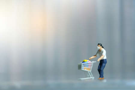 A men doing safe solo shopping at supermarket wearing a face mask. Miniature people figurines toys conceptual photography.の写真素材