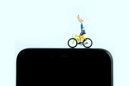 Bike cycling trainer and tracing app. A cycling above smartphone. Miniature people figure conceptual photography.の写真素材