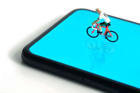 Bike cycling trainer and tracing app. A cycling above smartphone. Miniature people figure conceptual photography.の写真素材