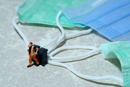 Cleaning workers carry disposable mask rubbish that has been used in the trash bin. Medical waste conceptual photo. Miniature people photography.の写真素材