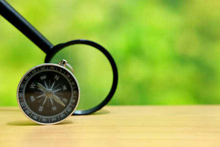 Black compass standing on wood table with magnifier glassの写真素材