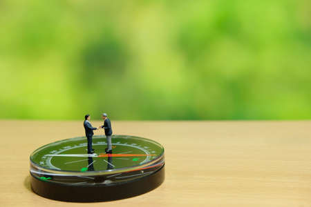 Business strategy conceptual photo - Two miniature businessman make handshake partnership agreement...