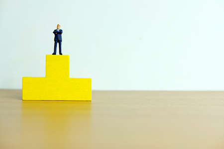 Miniature business concept - businessman standing on a podium to receive golden trophyの写真素材