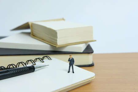 Miniature business concept - thinking a resolution. Mini figure with black white notesの写真素材