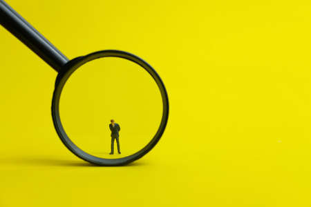 Miniature people headhunting concept - job vacancy, recruitment, searching for a candidate with yellow backgroundの写真素材
