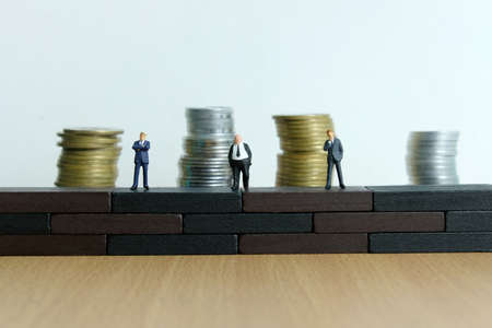 Miniature people - barrier to entry business concept. Group of businessman standing above brick wall...