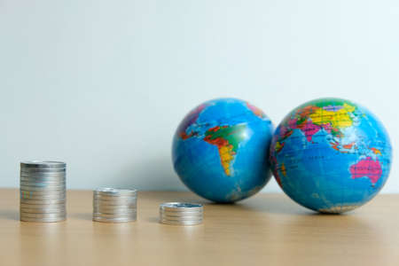 Global trade and financial concept - decreasing stack of coin in front of earth globeの写真素材