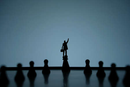 Business strategy conceptual photo - Silhouette of miniature of businessman pointing upside standing on castle pawn on a chessboardの写真素材