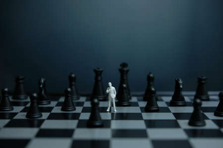 Business strategy conceptual photo - Miniature of businessman standing on chessboard