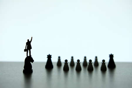 Business strategy conceptual photo - Silhouette of miniature businessman pointing upside, standing on a chess piece of horseの写真素材