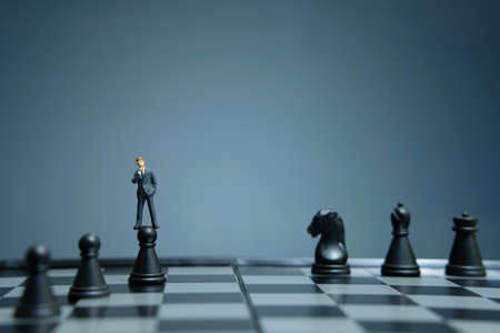 Business strategy conceptual photo - miniature businessman standing above castle pawn on a chessboardの写真素材
