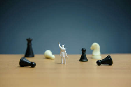 Miniature people strategic concept - businessman standing between losses or dropped pawnの写真素材