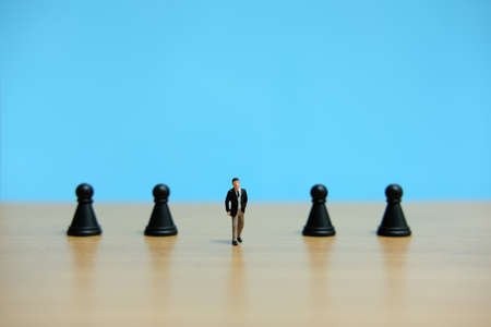 Business strategy conceptual photo - Miniature of businessman walking in the middle of pawn chess pieceの写真素材