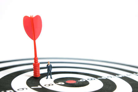 Business strategy conceptual photo - Miniature businessman with red arrow on a dartboardの写真素材