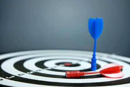 Wooden dartboard with red blue arrow on dark backgroundの写真素材