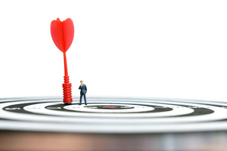 Business strategy conceptual photo - Miniature businessman with red arrow on a dartboardの写真素材