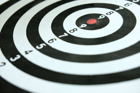 Conceptual photo of business strategy / accuracy - a red arrow that sticks directly in the center of the target dartboardの写真素材