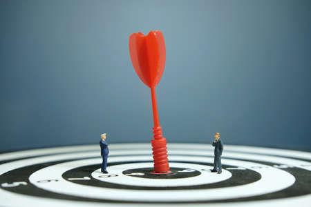 Business strategy conceptual photo - Miniature businessman with red arrow on a dartboardの写真素材