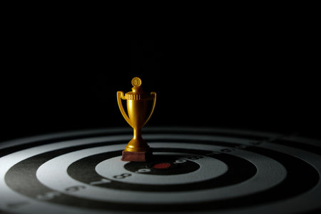 Conceptual photos of success and victory - a golden trophy that stands in the center of the target boardの写真素材
