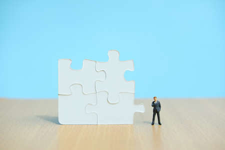 Conceptual photo of business strategy â miniature people standing in front of four joined jigsaw puzzleの写真素材