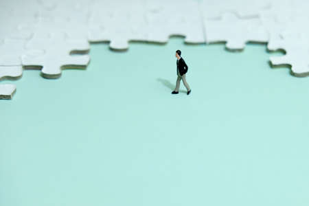 Business strategy conceptual photo - Miniature businessman walking in front of puzzle jigsawの写真素材