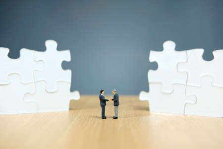 Business strategy conceptual photo - Miniature businessman make handshake partnership in the center...