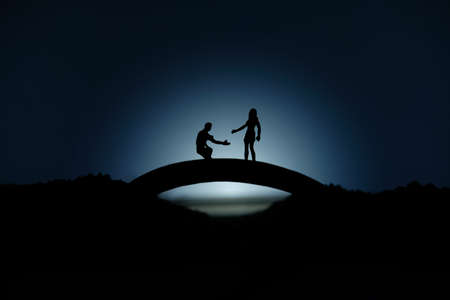 miniature people / toy photography - conceptual valentine holiday illustration. A man proposing a girl silhouette at the bridge under the moon lightの写真素材