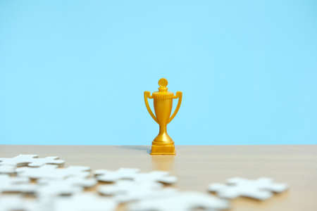 a golden trophy stands between a pile of puzzlesの写真素材