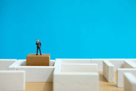 Business strategy conceptual photo - Miniature of businessman looking for solution on a labyrinth mazeの写真素材
