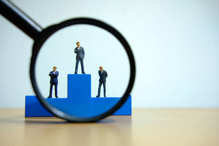 Business conceptual photo â miniature of businessman stands on wooden podiumの写真素材