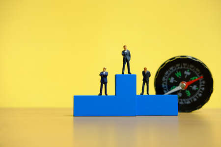 Business conceptual photo â miniature of businessman stands on wooden podiumの写真素材