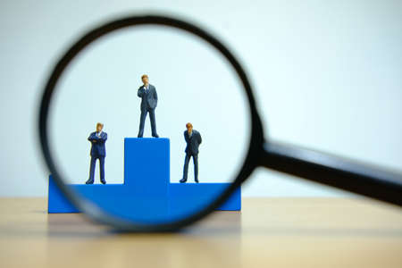 Business conceptual photo â€“ miniature of businessman stands on wooden podium