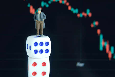 Miniature tiny people toys photography. People standing above dice, investing in stock market without analyzing the marketの写真素材