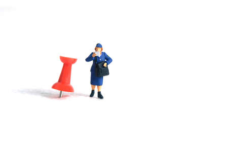 Miniature people toys conceptual photography. Courier pinpoint location pickup package delivery service. Postman with red push pin, isolated white background.の写真素材