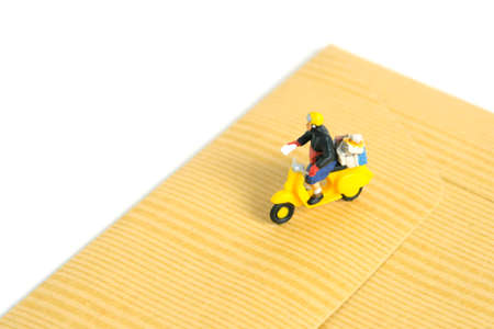 Miniature people toys conceptual photography. Mail postal courier delivery. Postman courier with envelope, isolated on white background.の写真素材