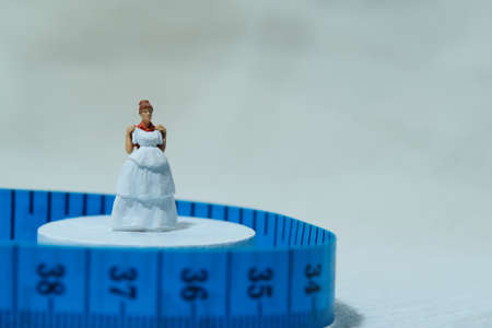 Women miniature people standing above measuring tape to fix her wedding dress. Image photoの写真素材