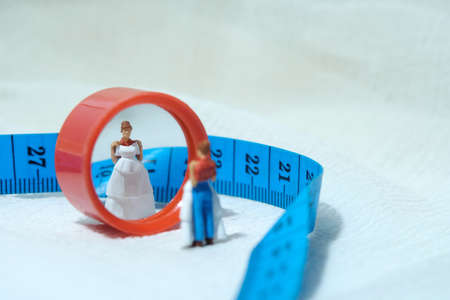 Women miniature people standing above measuring tape to fix her wedding dress. Image photoの写真素材