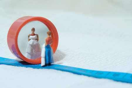 Women miniature people standing above measuring tape to fix her wedding dress. Image photoの写真素材