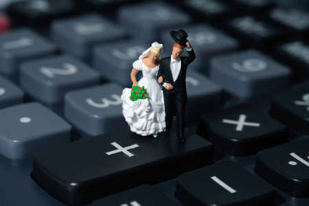 Bride and groom miniature people stand above calculator.  Wedding plan budget and financial conceptの写真素材