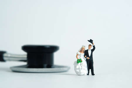 Wedding marriage and couple medical check-up concept miniature people toy photography. Bride and groom with stethoscope isolated on white background.の写真素材
