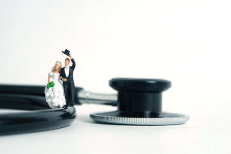 Wedding marriage and couple medical check-up concept miniature people toy photography. Bride and groom with stethoscope isolated on white background.の写真素材