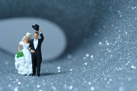 Bride and groom miniature people walk out on a tunnel full of silver and white bokeh light after wedding. Image photoの写真素材