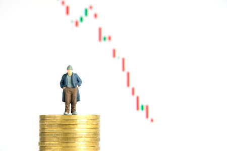 Miniature tiny people toys photography. People standing above coin stack does not have money or bankrupt, stock market candle chart fell down, isolated on white backgrounds.の写真素材