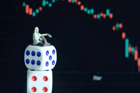 Miniature tiny people toys photography. People standing above dice, become poor man, gambling in stock market without analyzingの写真素材