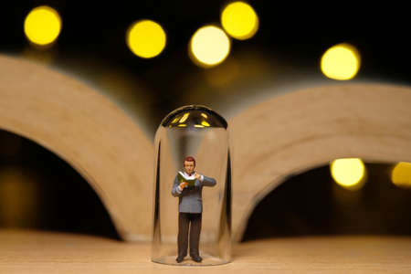home schooling, children reading book alone on quarantine or isolation time at night. Miniature tiny people toys photography with bokeh light backgroundの写真素材