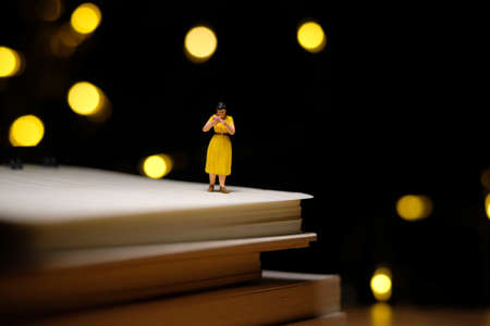 home schooling, children reading book alone on quarantine or isolation time at night. Miniature tiny people toys photography with bokeh light backgroundの写真素材