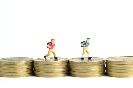 School admission budget.  Children or kids, walking above golden coin money stack. Miniature tiny people toys photography. isolated on white background.の写真素材